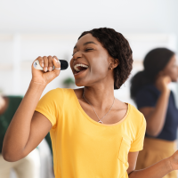 Smiling person having fund singing into a portable Karaoke Machine.