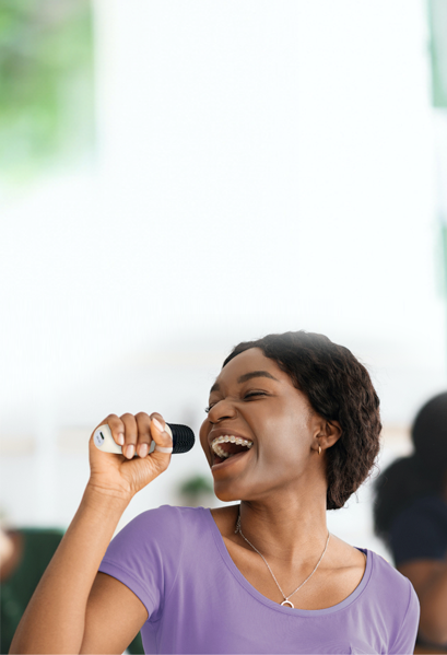 Smiling person having fund singing into a portable Karaoke Machine.